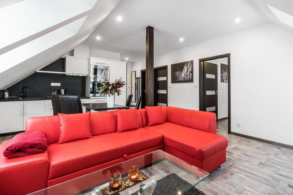 a red couch in a living room with a kitchen at Hotel Apartments Benešova 6 in Kutná Hora