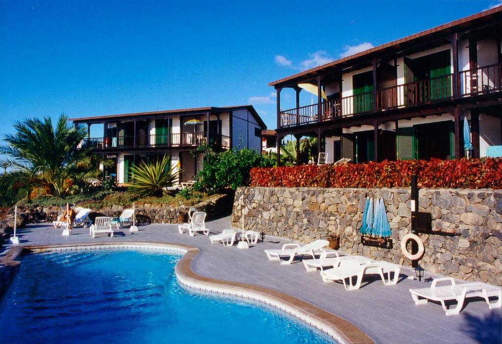 a resort with a pool and chairs and a building at Apartamentos Santa Ana - Adults Only in Playa de Santiago