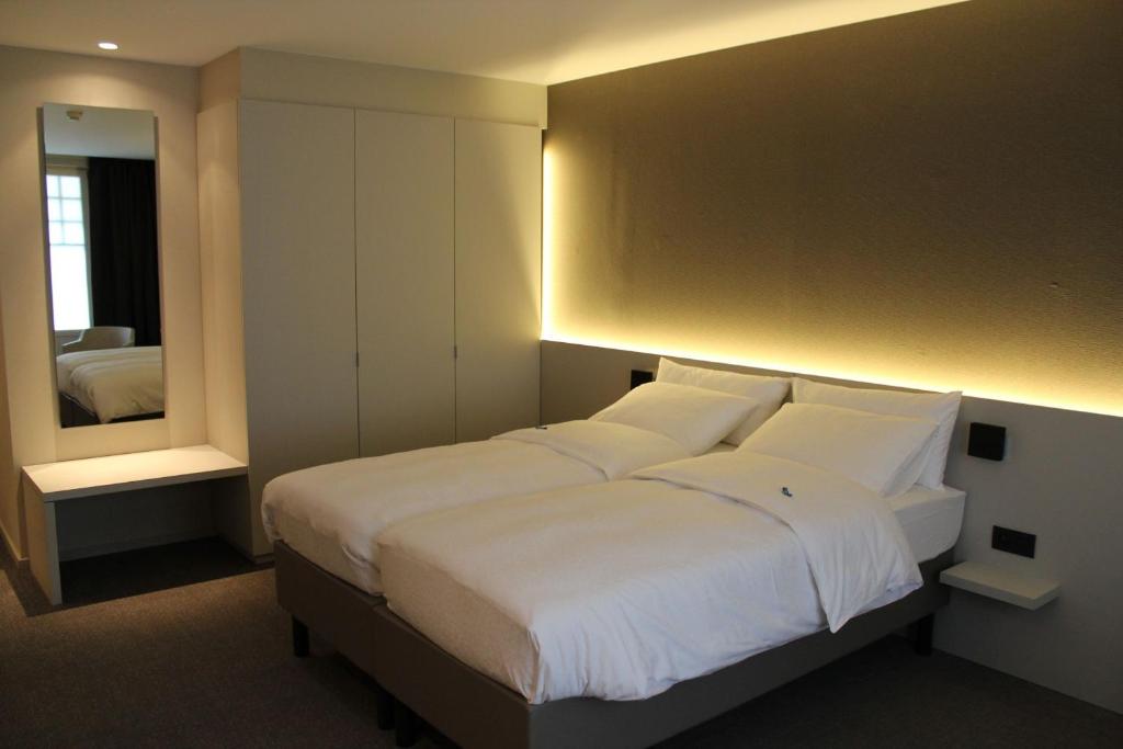a hotel room with a bed and a lamp at Hotel Astel in De Haan