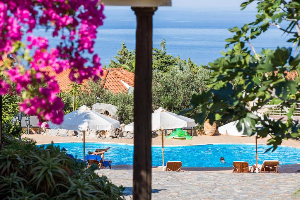 a swimming pool with chairs and umbrellas and the ocean at Monemvasia Village (ex Topalti) in Monemvasia