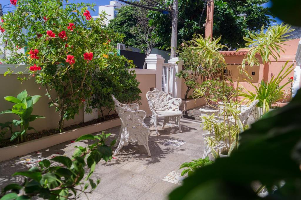 a garden with a white bench and red flowers at Pousada O Ninho in Salvador