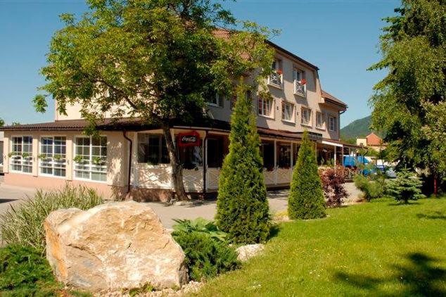 a large building with a large rock in front of it at Penzion Bystrica in Považská Bystrica