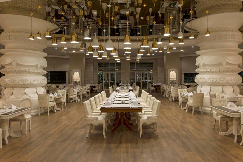 a dining room with a long table and white chairs at Delphin Imperial Lara in Lara
