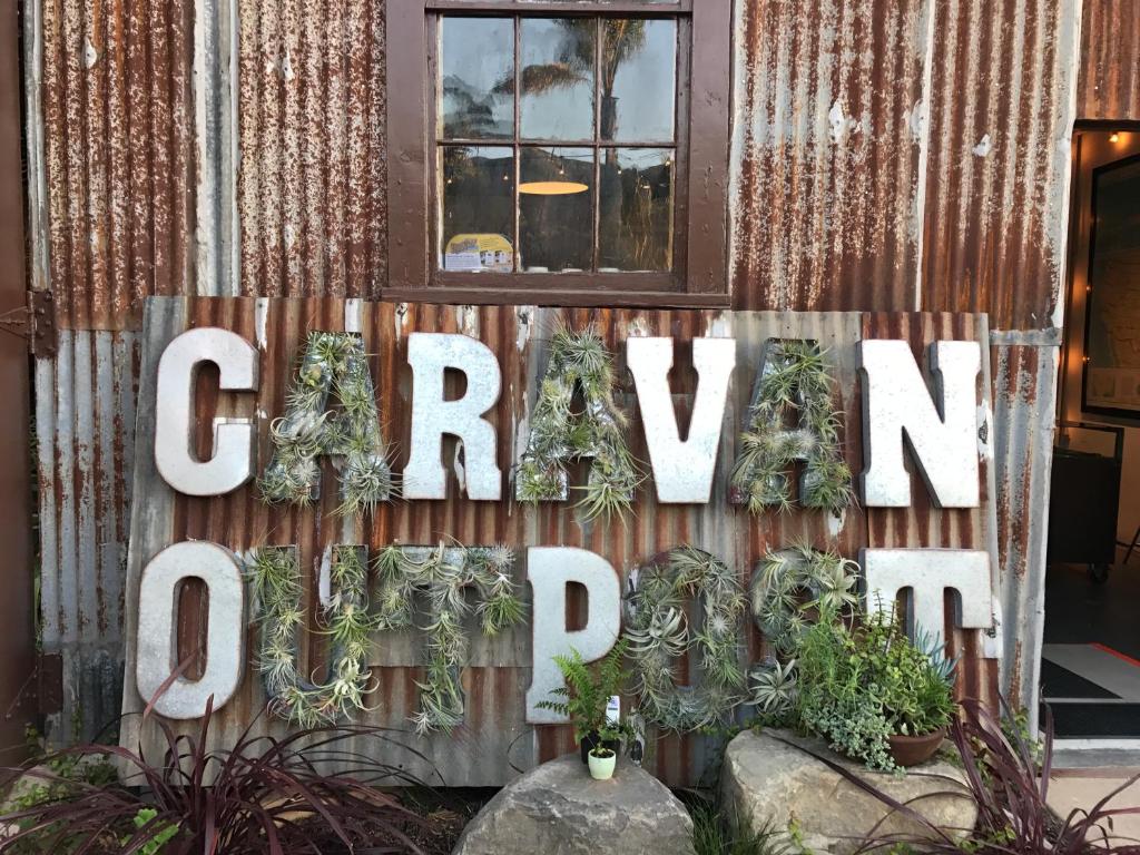 a sign on the side of a building with plants at Caravan Outpost in Ojai
