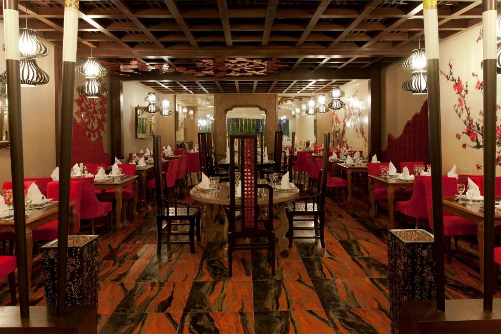 a dining room with red tables and chairs and a mirror at Delphin Imperial Lara in Lara