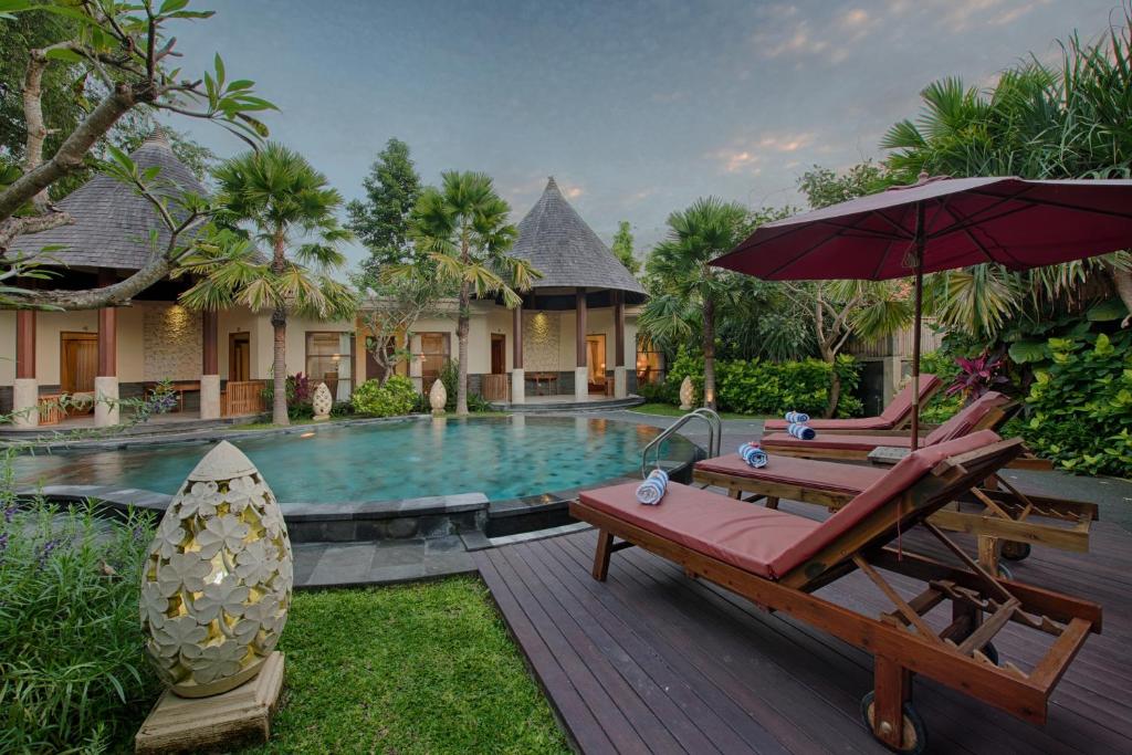 ein Resort mit einem Pool, 2 Stühlen und einem Sonnenschirm in der Unterkunft Kadiga Villas Ubud in Ubud