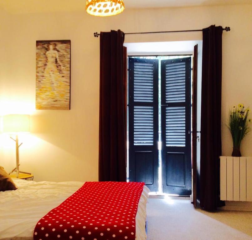 ein Schlafzimmer mit einer roten Decke auf einem Bett mit einem Fenster in der Unterkunft Résidence le 09 in Uzerche