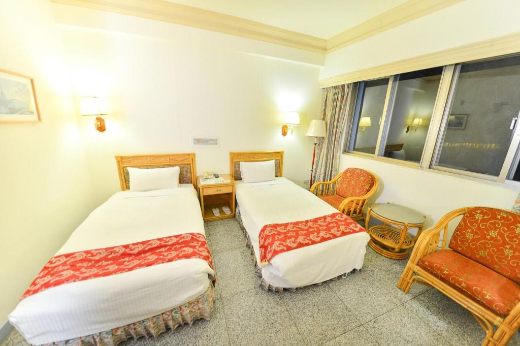 a hotel room with two beds and a chair at Dongpo Ti Lun Hotel in Xinyi