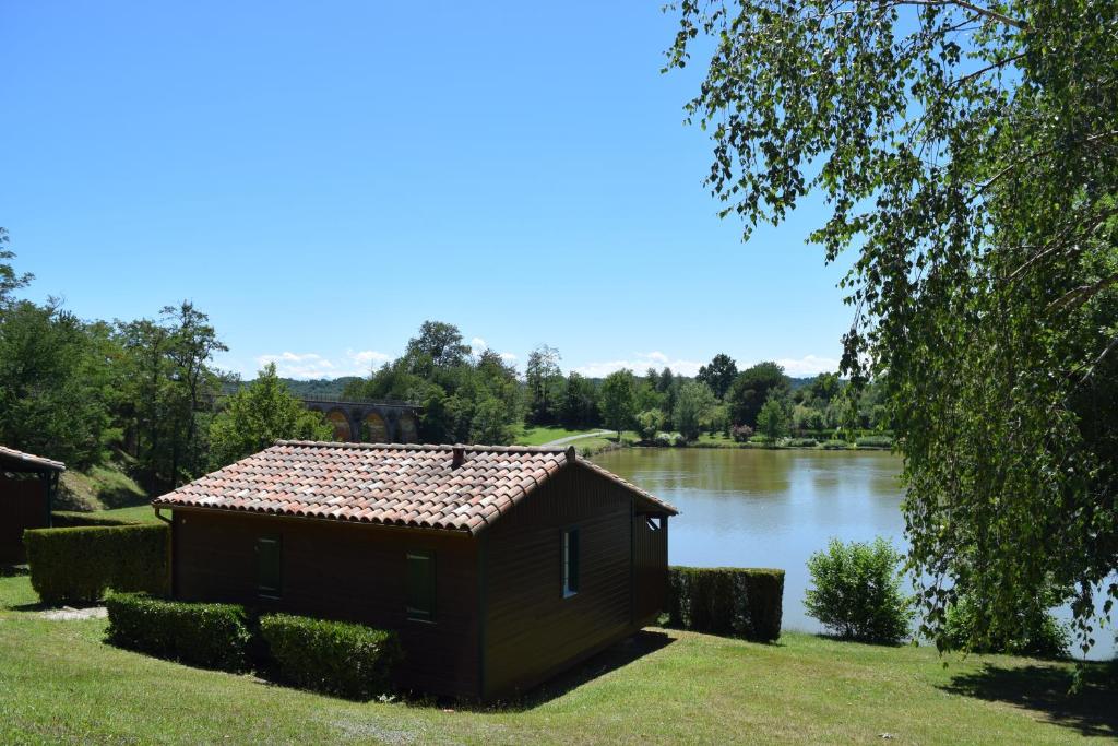 Camping - Village Vacances du Lac في Boulogne-sur-Gesse: مبنى صغير على جانب البحيرة