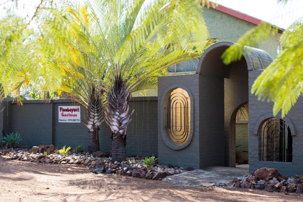 dos palmeras delante de un edificio en Flamboyant Guesthouse, en Bela-Bela