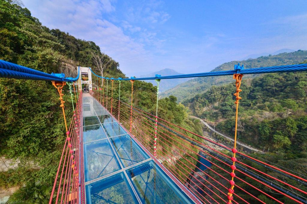 a suspension bridge over a river in the mountains at Dongpo Ti Lun Hotel in Xinyi