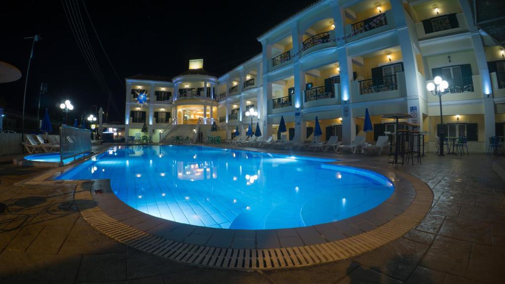 a large pool in front of a building at night at Aphrodite Hotel in Laganas