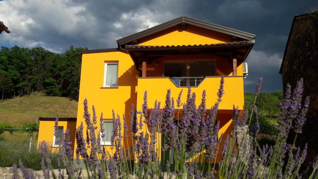 ein gelbes Haus mit lila Blumen davor in der Unterkunft Počitniška Hiša in Dobravlje