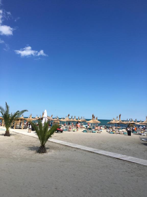 a beach with chairs and umbrellas and people at Sorriso Mamaia Nord in Mamaia Nord