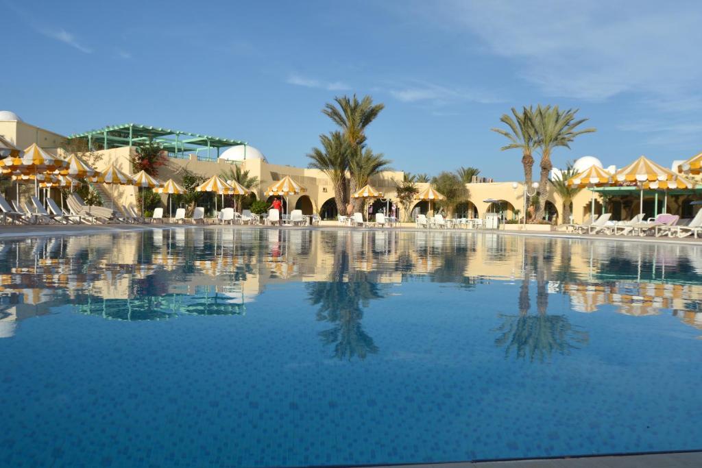 una gran piscina de agua con palmeras y sombrillas en Hotel Venice Beach- Families and Couples Only en Triffa