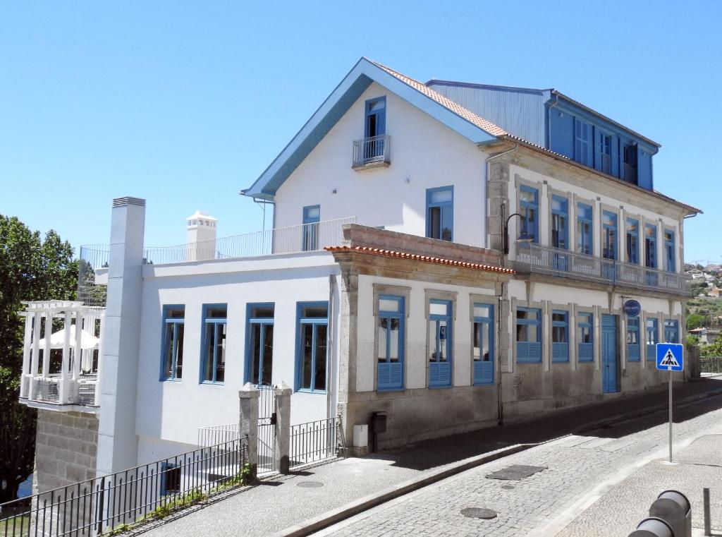 um antigo edifício branco com portas e janelas azuis em Des Arts em Amarante