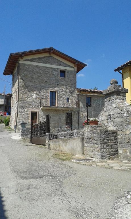 une ancienne maison en pierre avec une clôture devant elle dans l'établissement Agricola Tre Rii Sidreria, à Corniglio