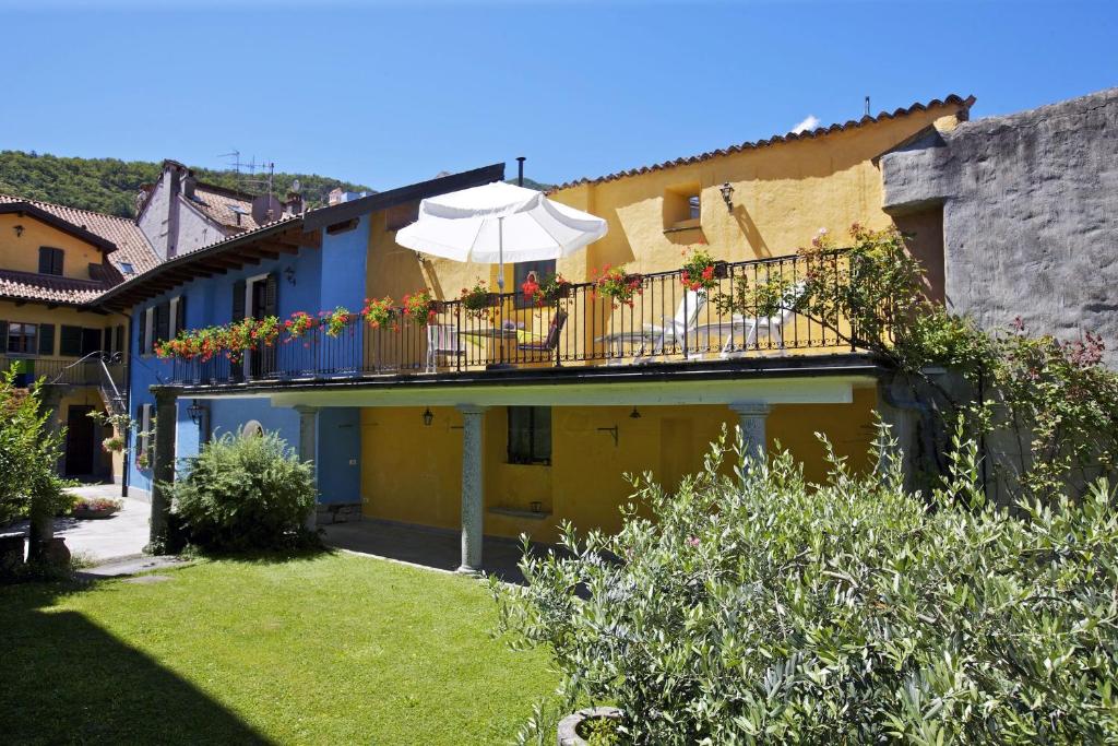 ein gelbes Gebäude mit Balkon und Sonnenschirm in der Unterkunft Casa Bel Giardino in Cannobio