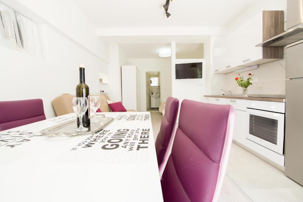 Una cocina blanca con sillas moradas y una mesa con una botella de vino. en Apartment Neyra 2, en Split
