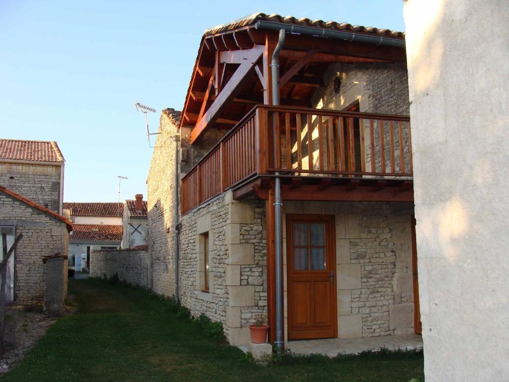 um edifício com uma varanda de madeira ao lado em Chambre d'hôte Au col de Cygne em Blanzac-lès-Matha