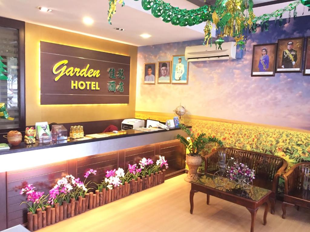 a restaurant with a bench in front of a counter with flowers at Pontian Garden Hotel in Pontian Kecil