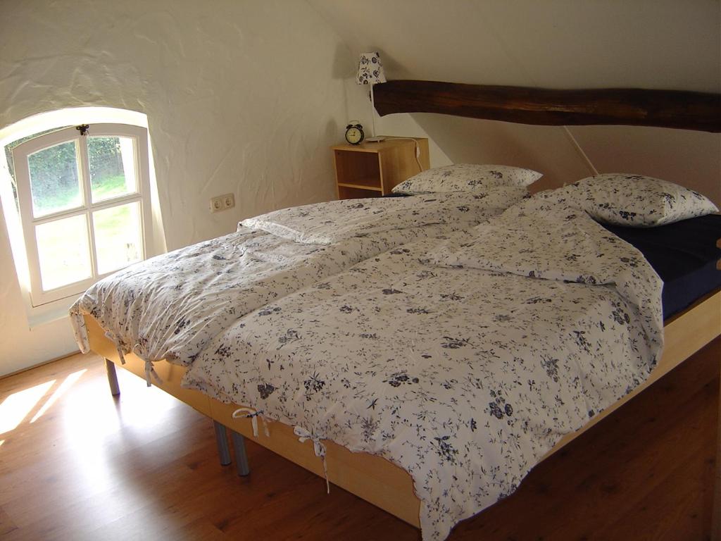 a bedroom with a bed with a comforter and a window at De Hopbel & Het Koevinkje in Liempde
