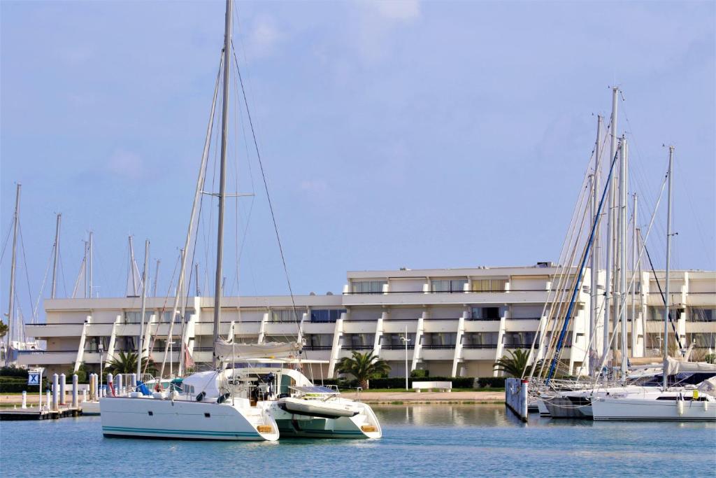 tres barcos atracados en el agua frente a un edificio en Rivages d'Ulysse Port Camargue, en Le Grau-du-Roi