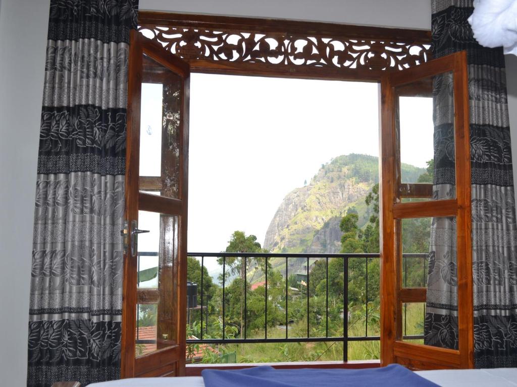 een kamer met een raam met uitzicht op een berg bij The Rock Face in Ella