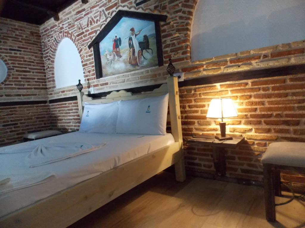 1 dormitorio con 1 cama en una pared de ladrillo en Sunset Suites en Sarandë