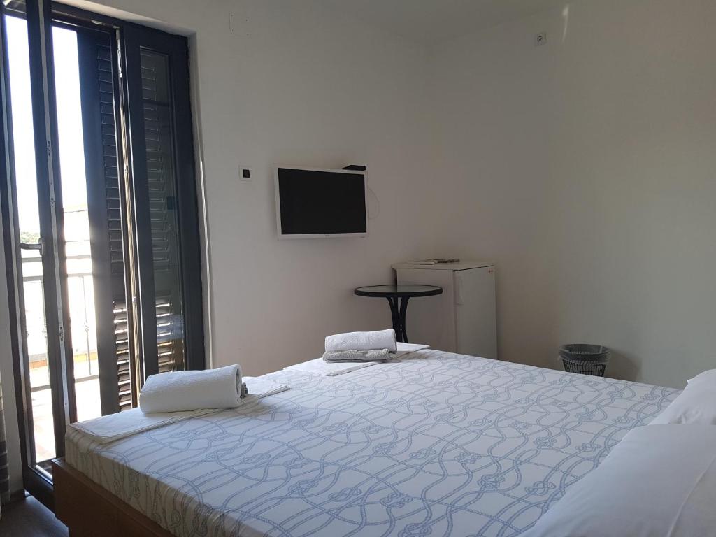 a white bedroom with a large bed and a tv at Guest House Sombrero in Senj