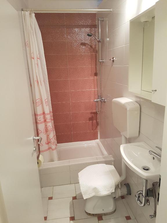 a bathroom with a toilet and a tub and a sink at Guest House Sombrero in Senj
