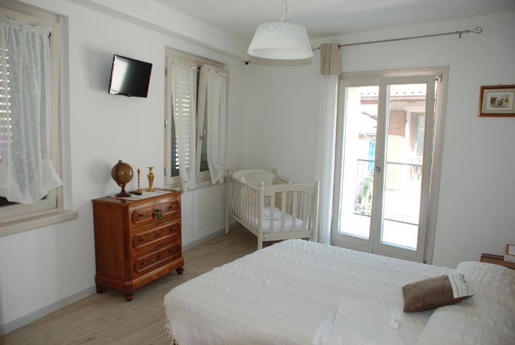 a white bedroom with a bed and a dresser and window at Casa Fanny in Limone sul Garda