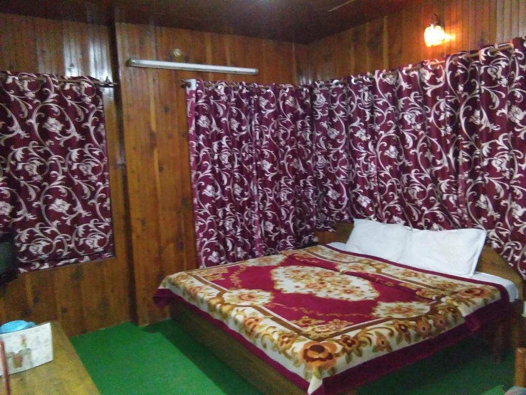 a bedroom with a bed with a red and white curtain at Hotel Hema Holiday Home in Manāli