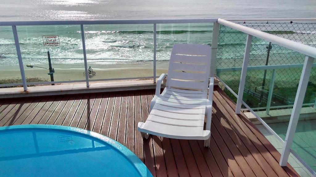una silla blanca sentada en una terraza junto a una piscina en Cobertura a Beira da Praia dos Ingleses, en Florianópolis