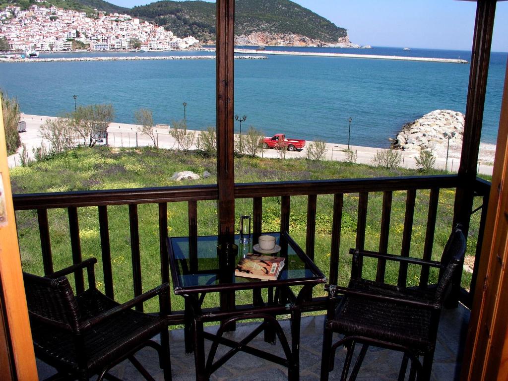 una mesa y sillas en un balcón con vistas al océano en Spitalia Studios, en Skopelos Town