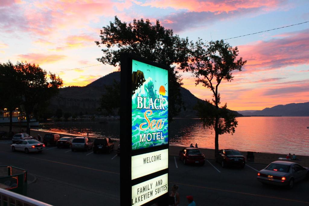 a sign in front of a parking lot next to a lake at Black Sea Motel in Penticton