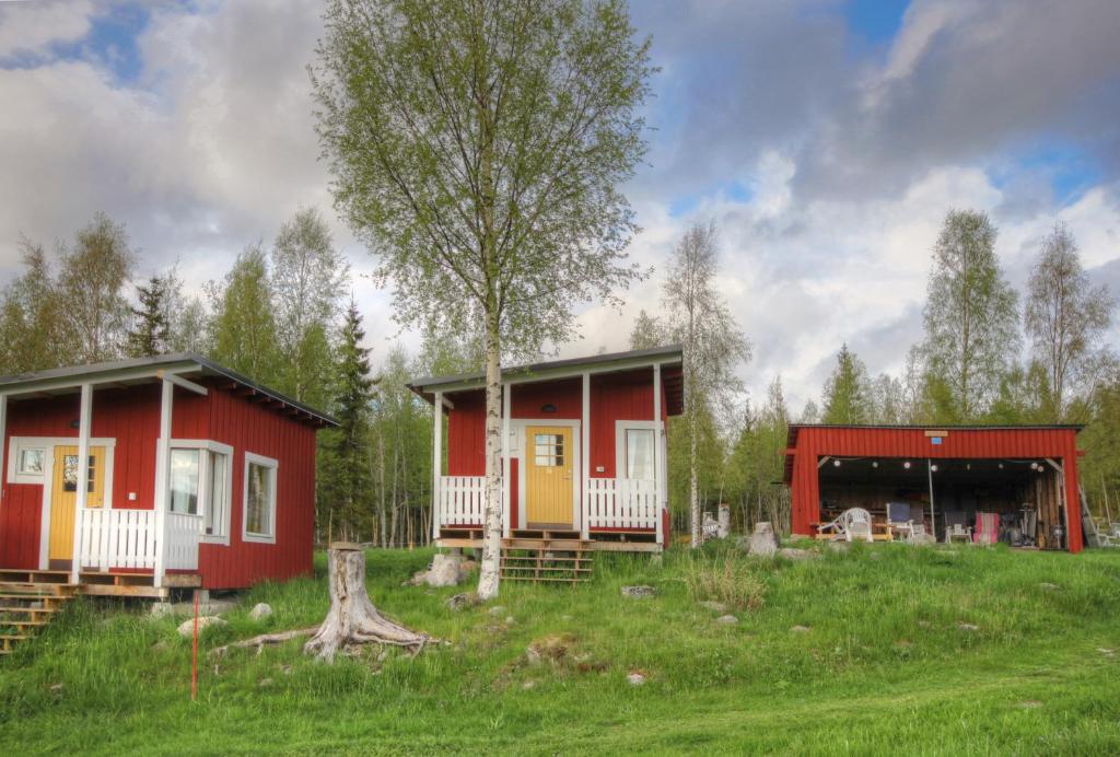 dos cabañas en un campo con un árbol en Getberget Hostel, en Ramvik