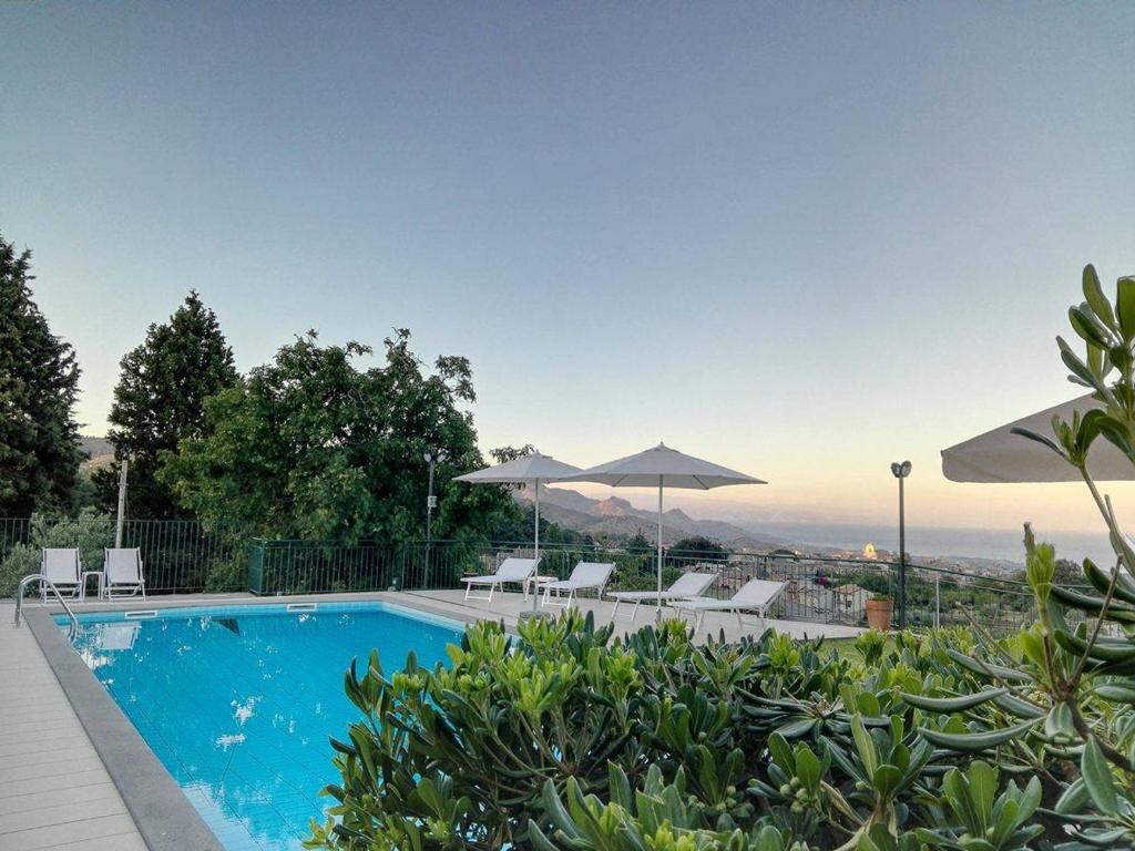 una piscina con sillas y sombrillas en Villa Capogrecale, en Piedimonte Etneo