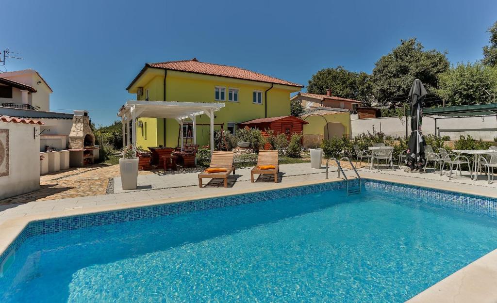 een zwembad met twee stoelen en een huis bij Apartments Dora Victoria Dream in Medulin