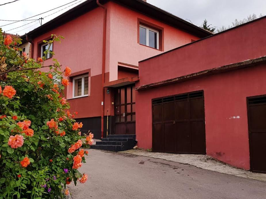 ein rotes Haus mit zwei Garagentüren und Blumen in der Unterkunft BTO Holiday Home in Sarajevo