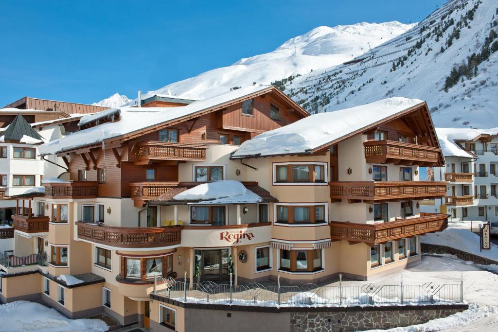 a hotel in the snow with mountains in the background at Hotel Regina in Obergurgl