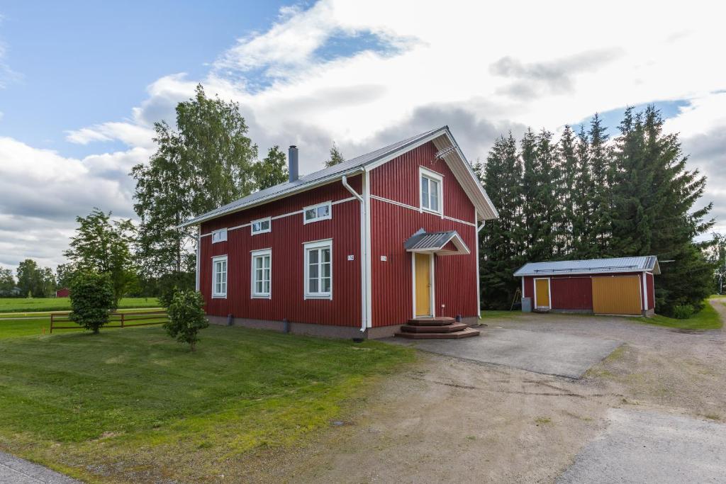 a red barn with a garage in a field at Erkin Haussi in Ilmajoki