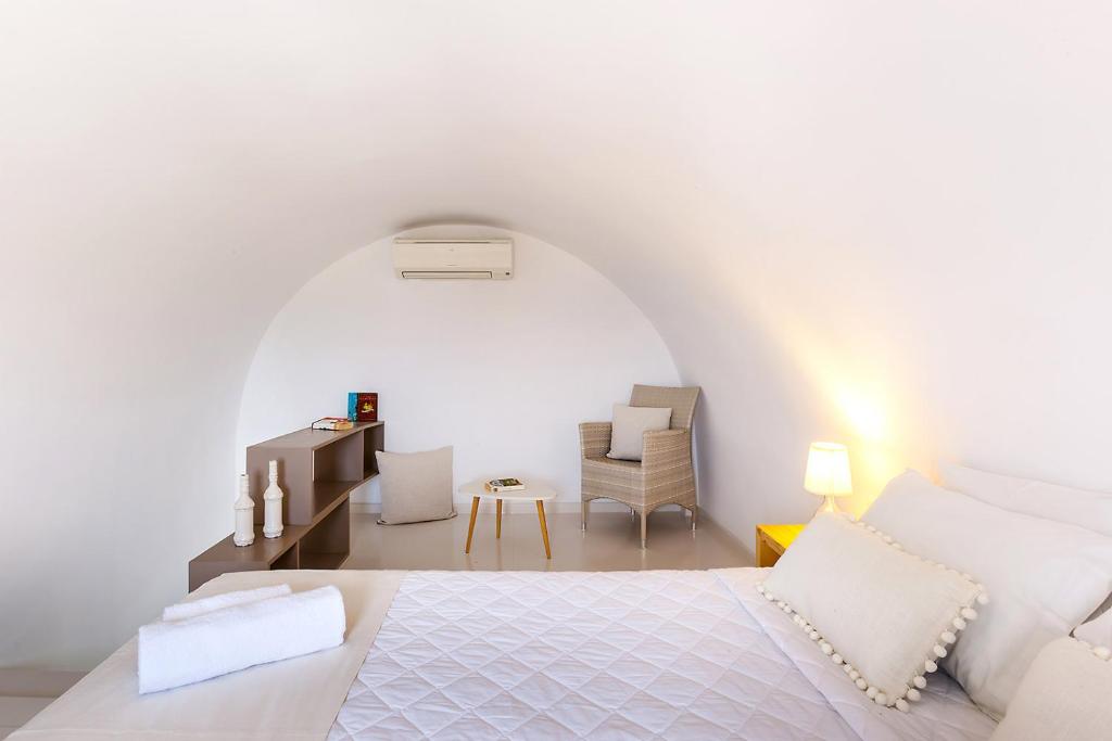 a white bedroom with a bed and a chair at Memories Beach Hotel in Monolithos