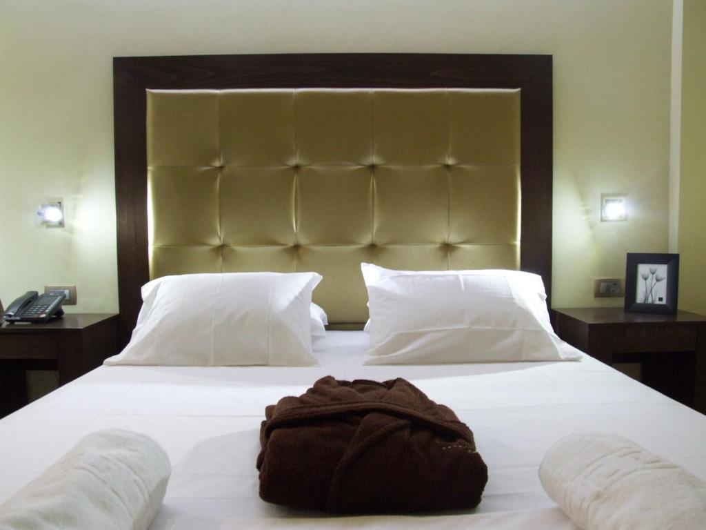 Una cama blanca grande con una toalla marrón. en Ellinis Hotel, en La Canea