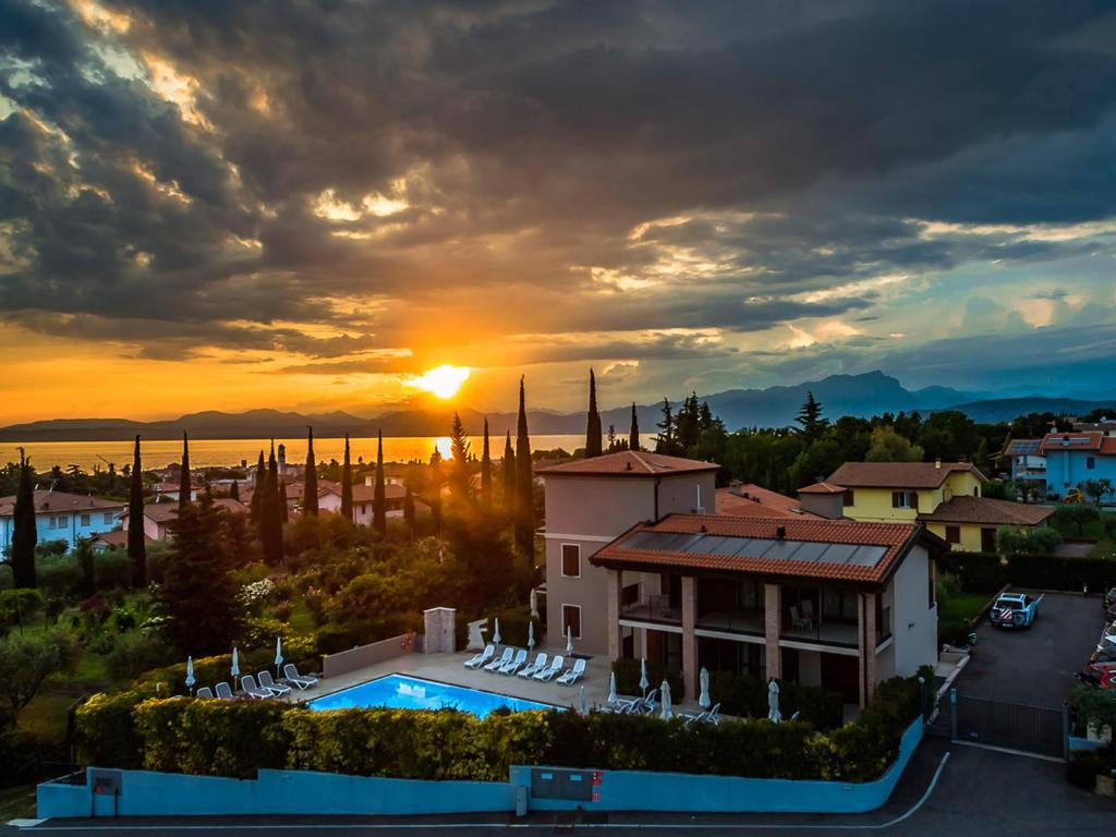 einen Sonnenuntergang über einer Villa mit einem Pool in der Unterkunft Hotel Relais Agli Olivi in Lazise