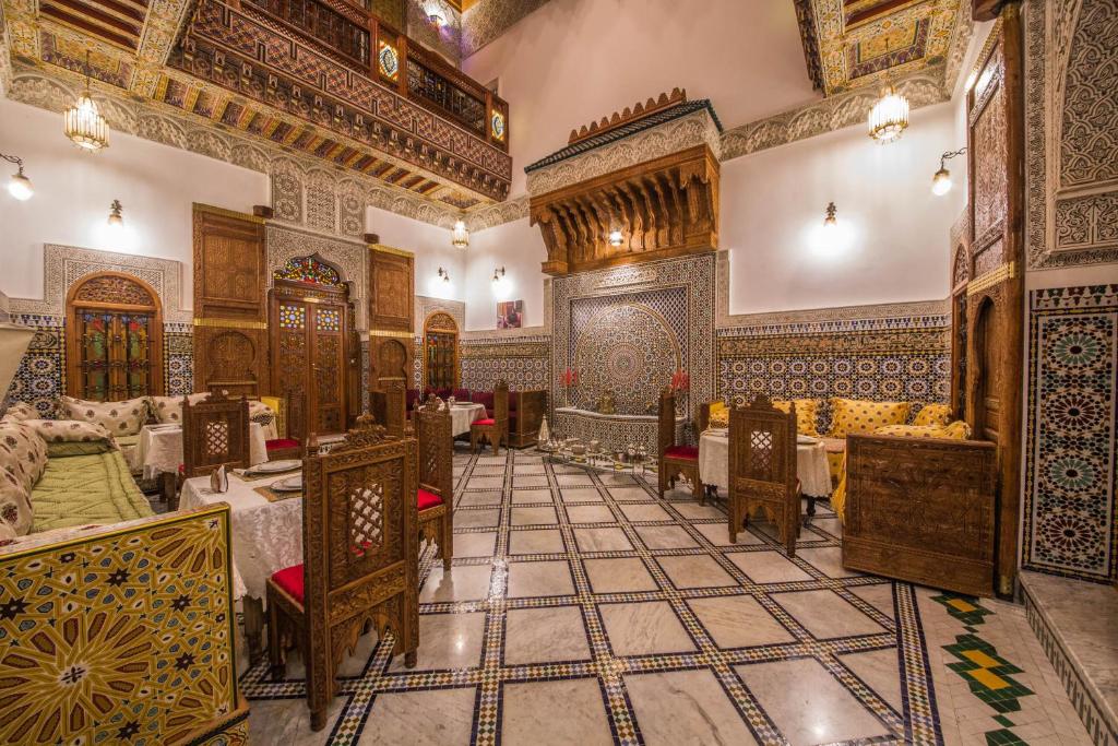 a dining room with tables and chairs in a building at Riad Ouliya in Fès