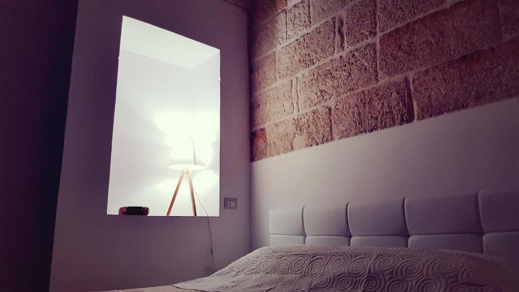 ポリニャーノ・ア・マーレにあるLa Maison A La Merのレンガの壁、ベッド付きのベッドルーム1室