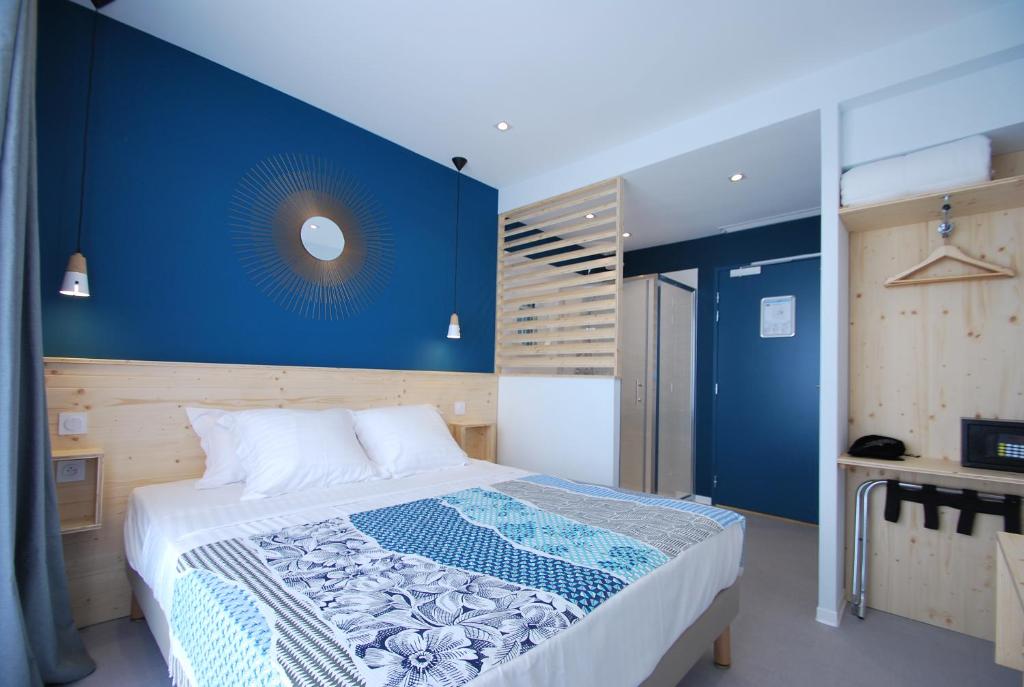 a bedroom with a large bed with a blue wall at Hôtel Café Miramar in Le Grau-du-Roi