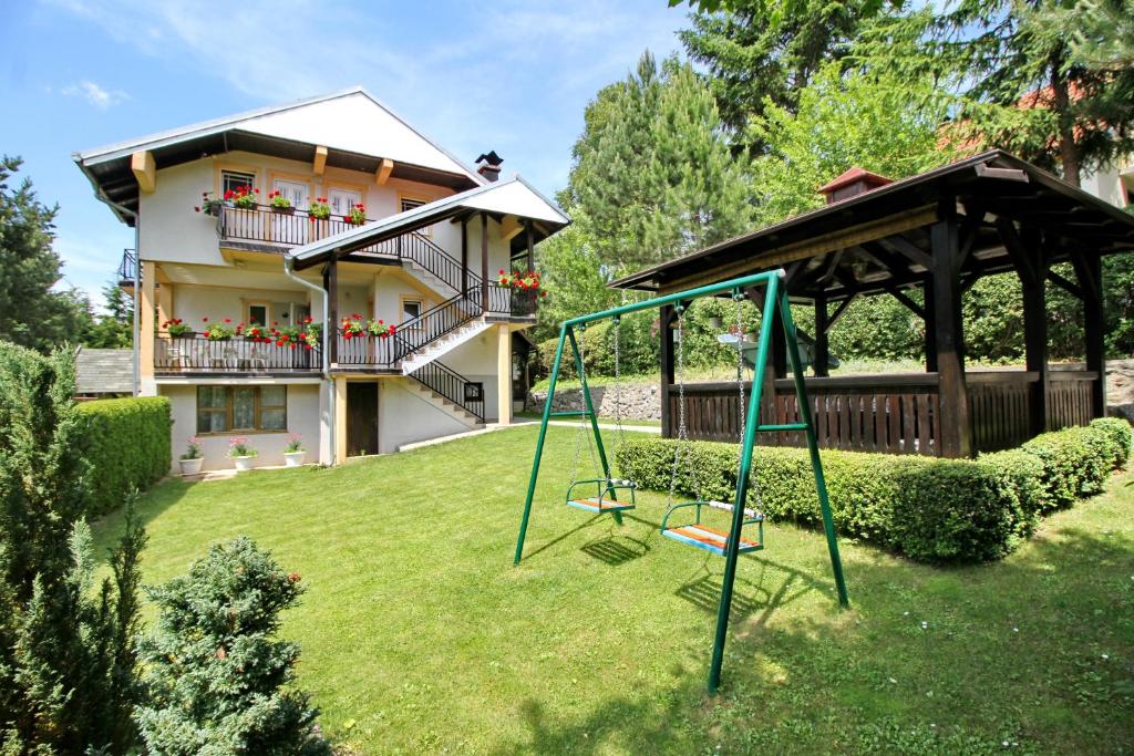 a yard with a swing and a house at Apartments Junior in Zlatibor