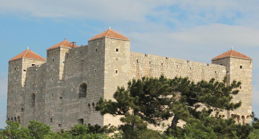 een groot kasteel met twee torens bovenop een heuvel bij Guesthouse Donko 1 & 2 in Senj